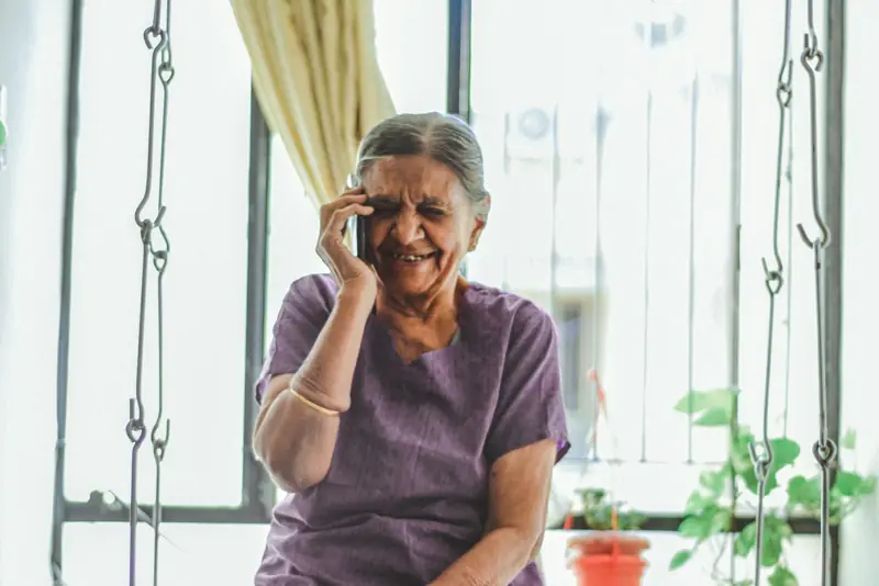 An older woman smiling on a phone call