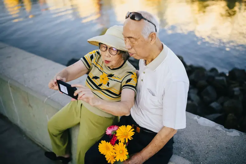 An older Asian couple looking at a phone together